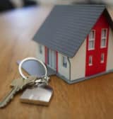 A small toy house with key and padlock symbolising a successful contractor mortgage sale