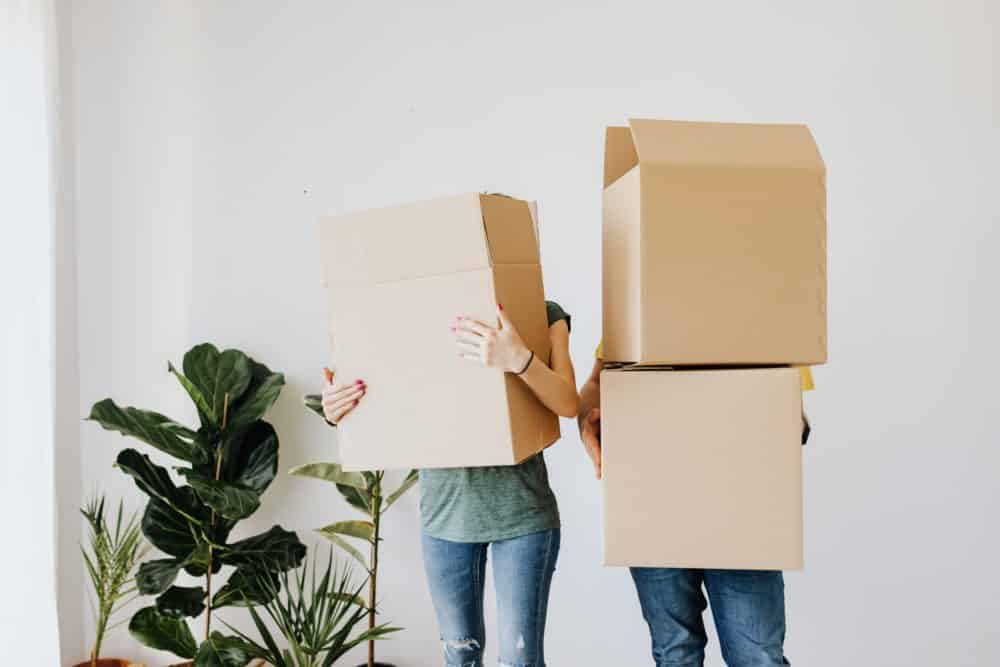 Two people with boxes moving into their new home