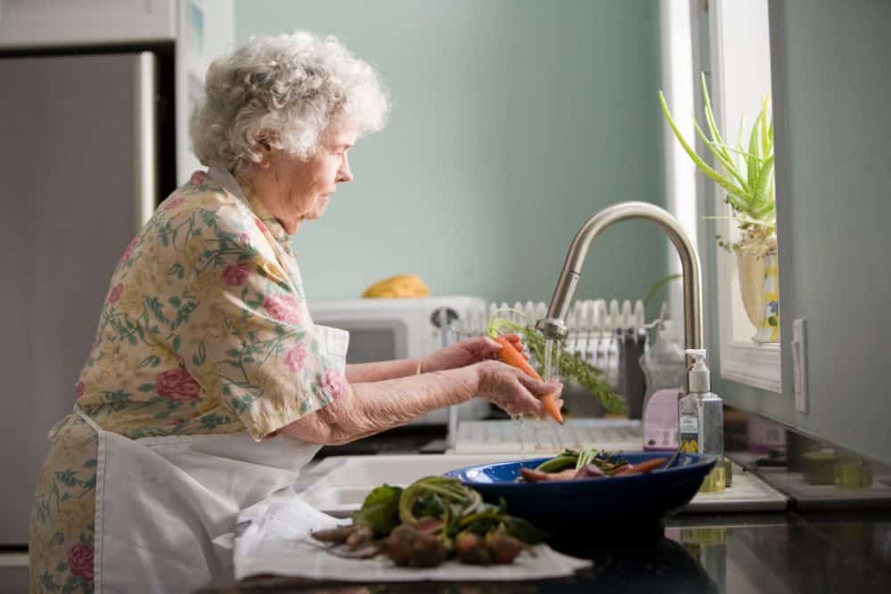 A lady washing vegetables at a sink